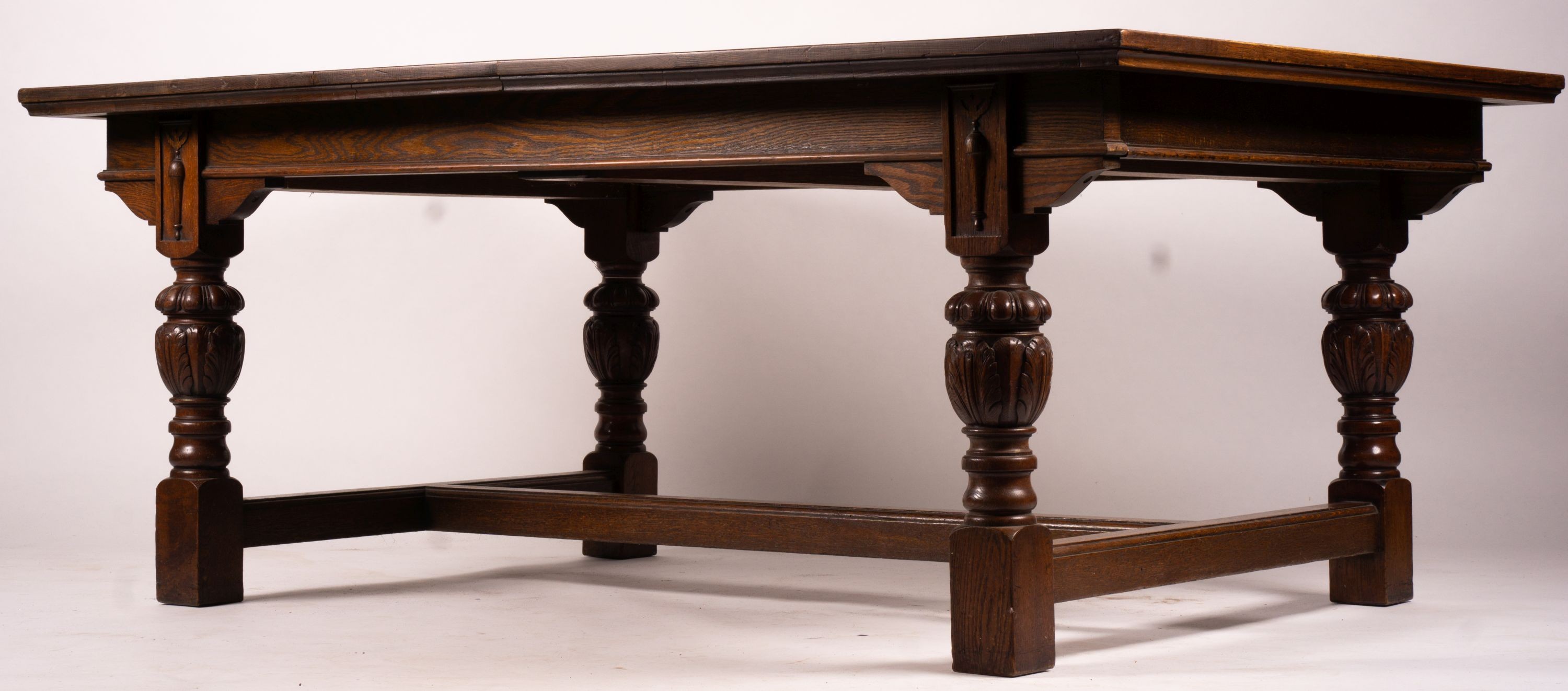 A 17th century style carved rectangular oak extending dining table with 'H' stretcher, 300cm extended, two spare leaves, width 121cm, height 75cm